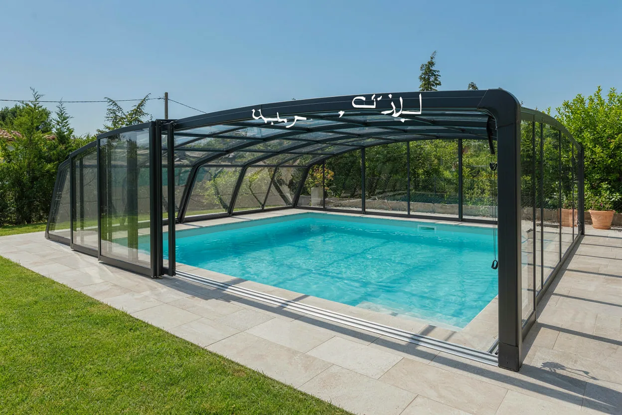 Abri de piscine bas coulissant sur une piscine turquoise
