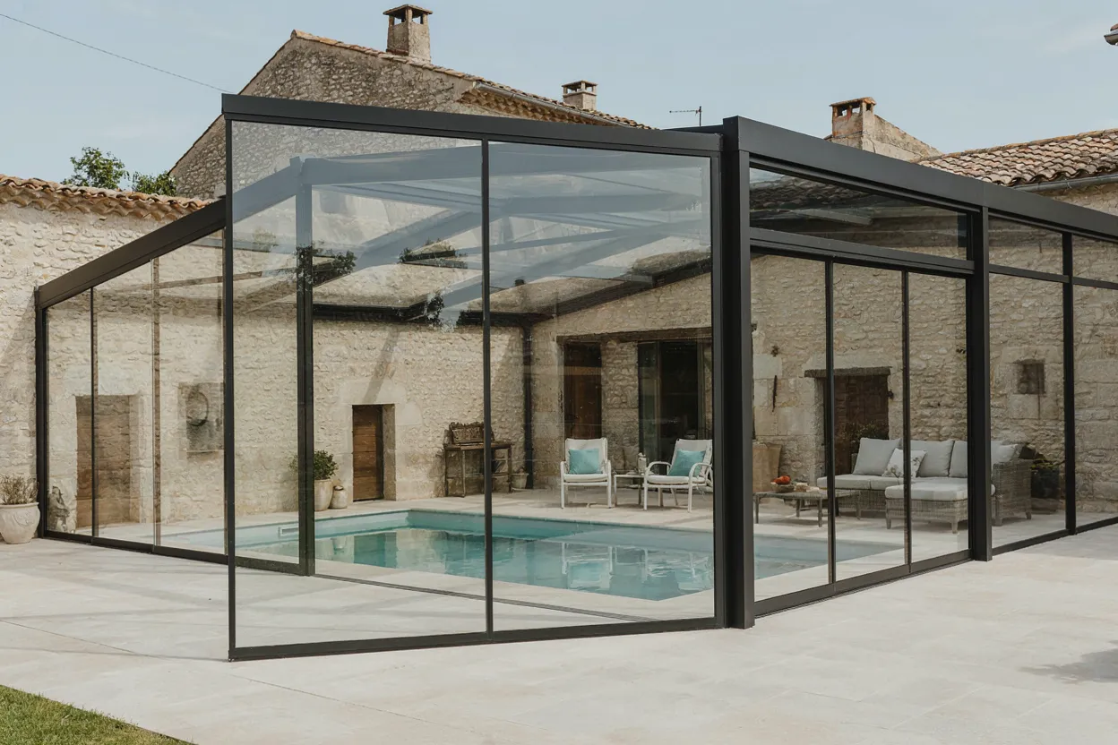Verrière de piscine adossée à une maison en pierre